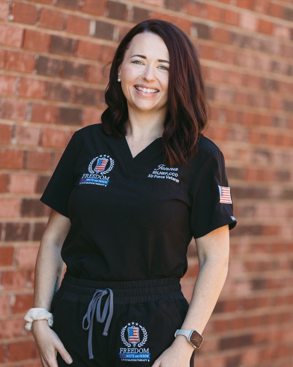 Jenna Lutz smiling in black Freedom IV scrubs in front of a brick wall